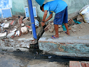 Cândido mostra que a água utilizada em banho na sua casa sai na calçada e escorre na rua a céu aberto. (Foto: Giselle Dutra / G1 CE)