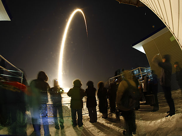 Pessoas assistem ao lançamento da Soyuz na base de Baikonur, no Cazaquistão (Foto: AP )