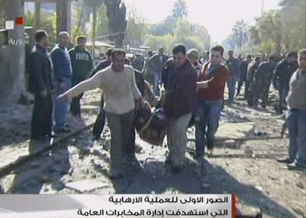 Homens carregam o corpo de uma vítima de atentado em Damasco (Foto: AFP/TV síria)