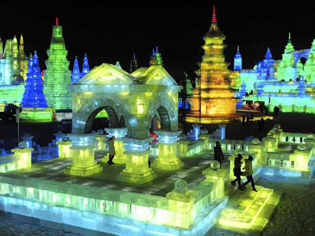 Turistas visitam esculturas de gelo no 13º Mundial de Neve em Harbin, na província de Heilongjiang, na China. Artistas criam estruturas de gelo em tamanho real. As esculturas ganham um toque especial com jogo de luzes coloridas.  (Foto: Sheng Li/Reuters)