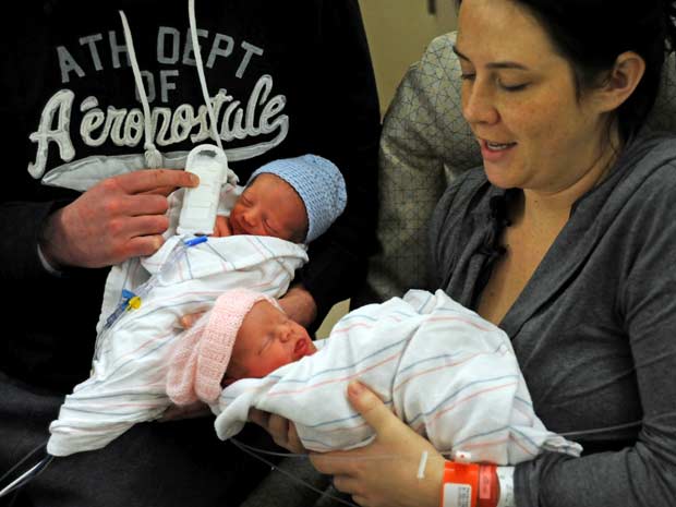 Os bebês Beckett e Freya posam para fotos no colo de seus pais, Darryl Humenny e Stephanie Peterson, neste domingo (1º) em maternidade do condado de Hennepin, em Minneapolis, no estado do Minnesota. Os gêmeos nasceram com horas de diferença -Beckett às 18 (Foto: AP)
