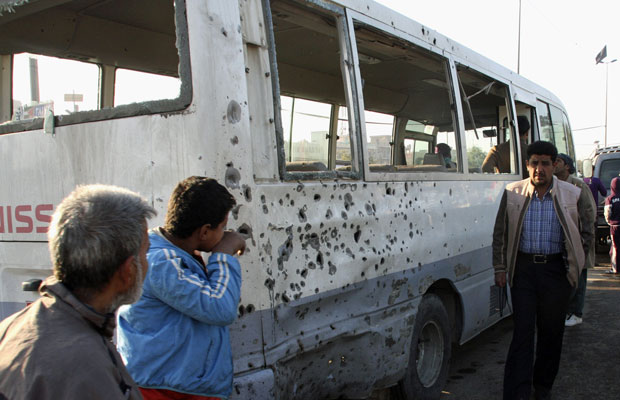 Moradores observam ônibus atingido por explosão na cidade Sadr (Foto: Kareem Raheem/Reuters)