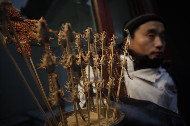 Vendedor comercializa espetinhos de escorpião em Pequim, na China. (Foto: Eugene Hoshiko/AP)