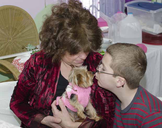 No colo de Sally Leone Montufar, Lucy ganha beijo de Sean Hebron, de 11 anos, um dos garotos para quem ela trabalha como 'terapeuta canina' (Foto: AP)