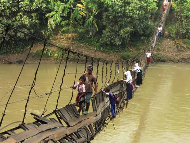 Crianças arriscam-se em ponte danificada sobre o Rio Ciberang, em Lebak, na província indonésia de Banten, para ir à escola nesta quinta-feira (19). A ponte foi atingida por uma tempestade que atingiu a região na semana passada (Foto: AP)