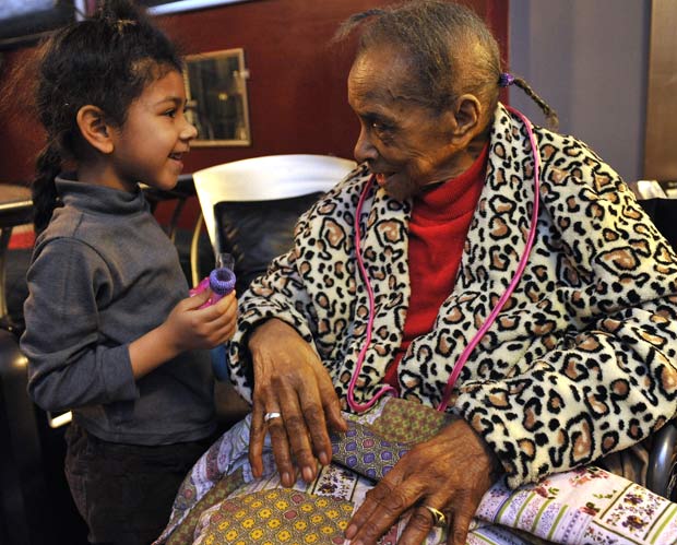 A norte-americana Texana Hollis, 101, conversa com a neta da vizinha que a abrigou depois do despejo, em Detroit (Foto: AP)