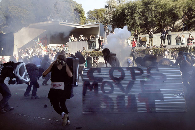 Manifestantes correm entre o gás lacrimogêneo jogada pela polícia durante conflitos no sábado (28) (Foto: AP/Michael Macor/San Francisco Chronicle)