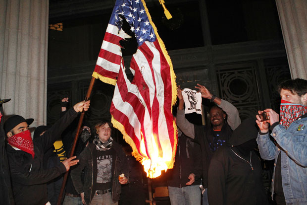 O movimento chegou a queimar uma bandeira americana retirada de um prédio do governo em Oakland (Foto: Beck Diefenbach/AP)