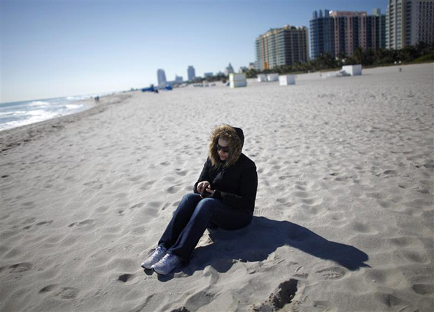 Turista vestindo jaqueta em pria de South Beach, em Miami (Foto: Carlos Barria / Reuters)