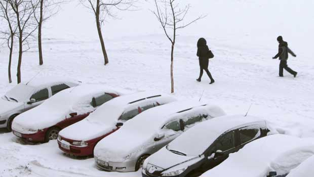 Moradores caminham próximo a carros cobertos de neve em Minsk, Belarus, nesta terça-feira (7) (Foto: AP)