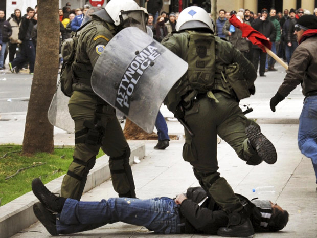 Policial chuta manifestante durante protestos em Atenas, na Grécia, nesta sexta-feira (10). (Foto: John Kolesidis/Reuters)