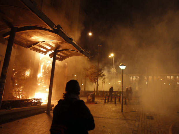 Franquia da Eurobank em Atenas, na Grécia, é consumida pelo fogo durante protestos realizados neste domingo. (Foto: Thanassis Stavrakis/AP)