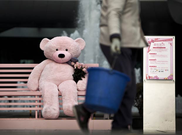 Urso de pelúcia gigante é colocado em banco em shopping de Pequm, na China, neste domingo (12) (Foto: Andy Wong/AP)