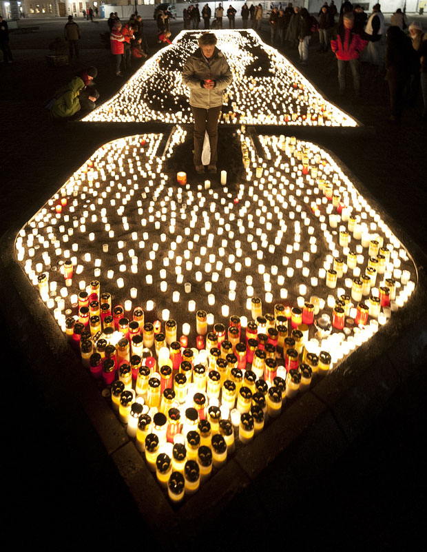 Moradores de Dresden, na Alemanha, foram às ruas da cidade e acenderam velas para lembrar nesta segunda-feira (13) os 67 anos desde que a cidade foi bombardeada pelos Aliados em 1945, durante a II Guerra Mundial. (Foto: Robert Michael/AFP)