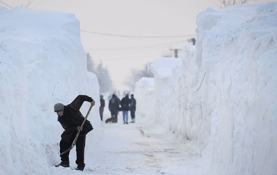 14 de fevereiro - Mulher cava a neve para abrir caminho até sua casa na vila de Glodeanu Silistea, a 100 km de Bucareste, na Romênia