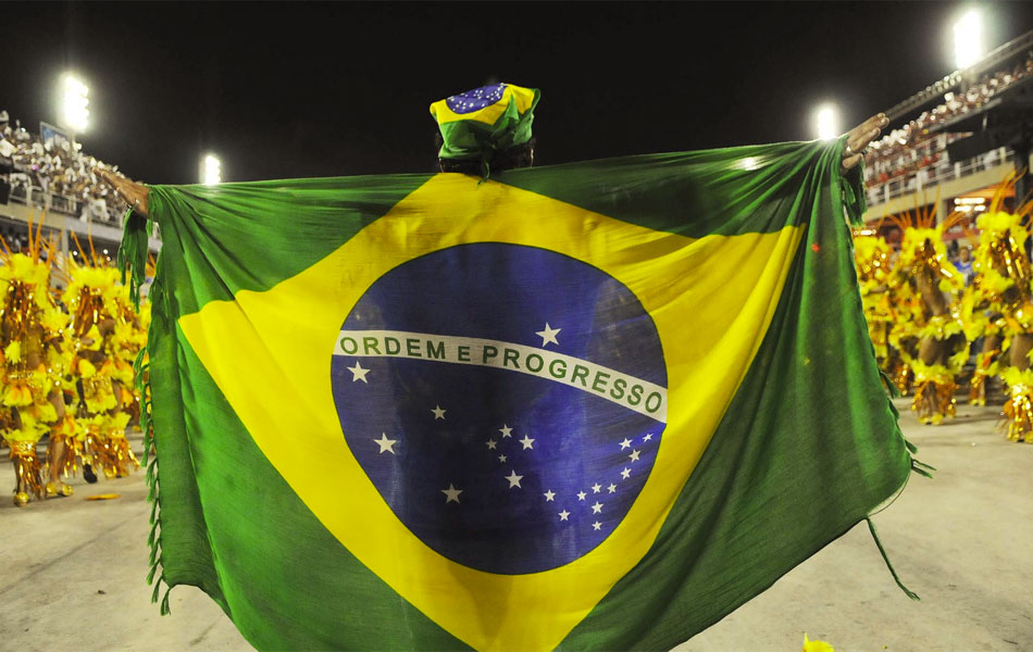 Bandeira do Brasil serve de 'capa' de folião no meio da avenida durante desfile da Beija-Flor.