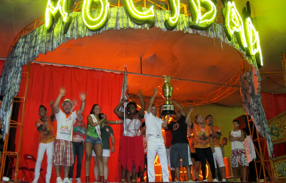 Integrantes da Mocidade Alegre comemoram a vitória com o troféu de campeã na quadra da escola