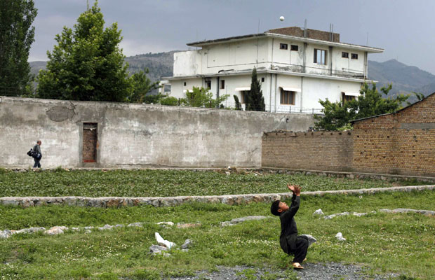 Menino brinca com bola em frente à casa que abrigou o ex-líder da rede al-Qaeda Osama bin Laden, em Abbottabad, no Paquistão. As forças paquistanesas informaram que começaram neste sábado (25) a demolição da casa onde o terrorista foi morto pelos american (Foto: Reuters)
