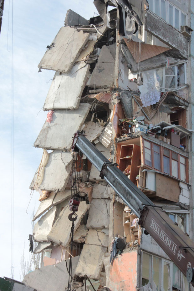 Máquina usada para remover escombros é vista em frente a paredes e pisos desmoronados do edifício em Astracã (Foto: AP/Assessoria do Ministério de Situações de Emergência em Astracã)