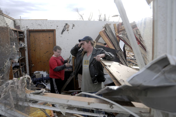 Gene Byrd e seu filho Devyn Byrd, de 14 anos, observam os estragos causados em casas de sua vizinhança em Harrisburg, Illinois (Foto: AP/Paul Newton/The Southern Illinoisan)