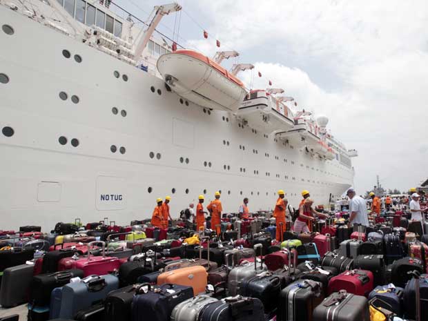 Tripulantes do navio de cruzeiro foram os primeiros a desembarcar para organizar bagagens dos passageiros. (Foto: Gregorio Borgia / AP Photo)