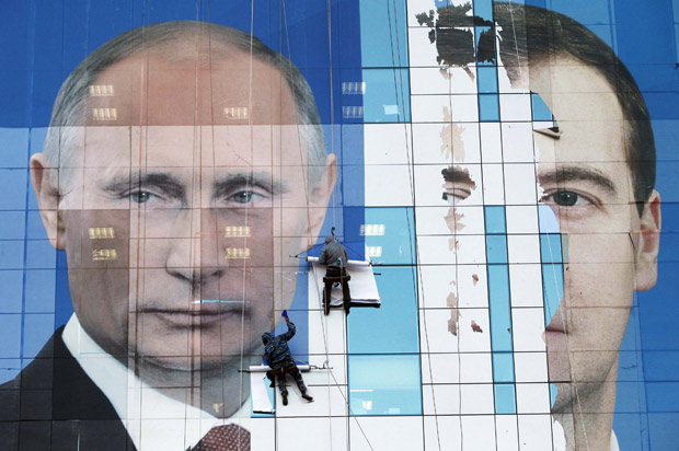 Trabalhadores fixam cartaz com os rostos do primeiro-ministro Vladimir Putin, candidato à Presidência da Rússia, e o atual presidente, Dimitri Medvedev (Foto: Eduard Korniyenko / Reuters)