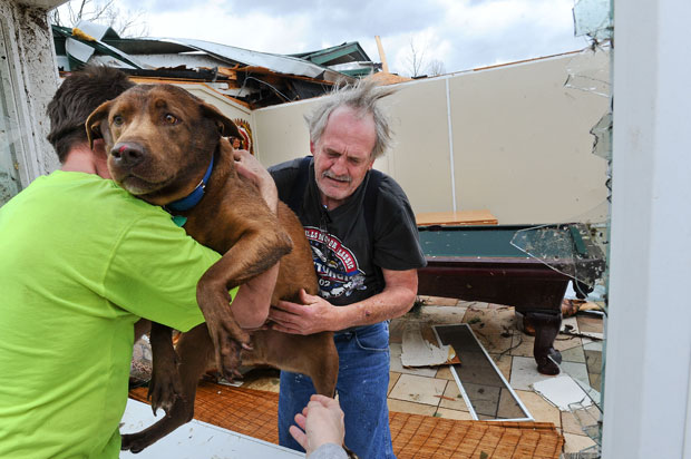 O americano passa sua cachorra pela janela para um vizinho após encontrá-la na casa destruída (Foto: AP/Gary Cosby Jr./The Decatur Daily)