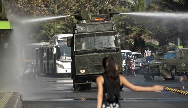 Estudante encara veículo militar durante protesto nesta quinta-feira (15) em Santiago do Chile (Foto: AFP)