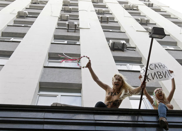 As feministas subiram na fachada do prédio para protestar com cartazes e pinturas no corpo (Foto: Anatolii Stepanov/Reuters)