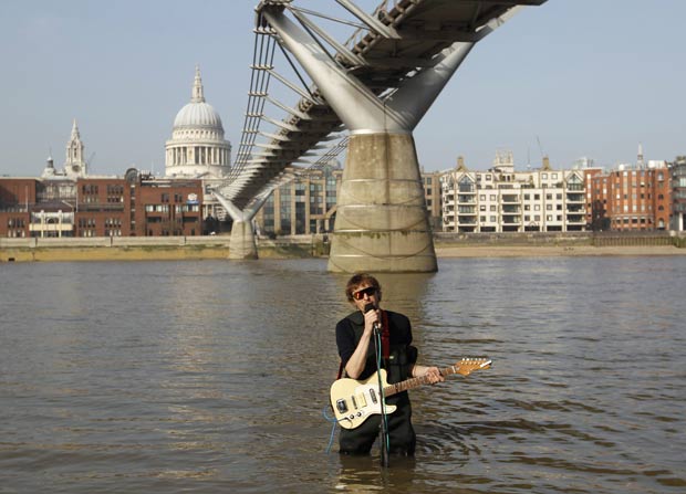 Música toca guitarra dentro do rio Tâmisa. (Foto: Andrew Winning/Reuters)
