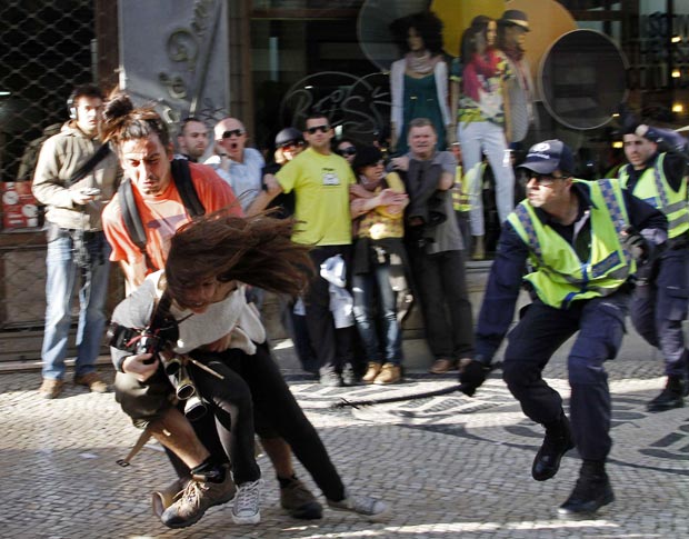 Policial desfere um golpe com um bastão contra a fotógrafa Maria Melo, durante greve geral de servidores em Lisboa (Foto: Hugo Correia / Reuters)