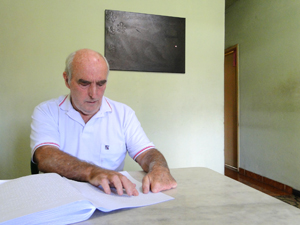 Seu Juvenal Filho lendo uma revista em braille. (Foto: Pedro Cunha/G1)