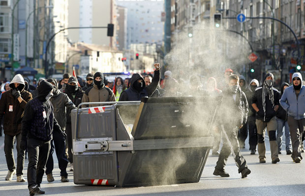 Manifestantes passam por contêiner de lixo em Burgos, durante greve espanhola  (Foto: Cesar Manso/AFP)