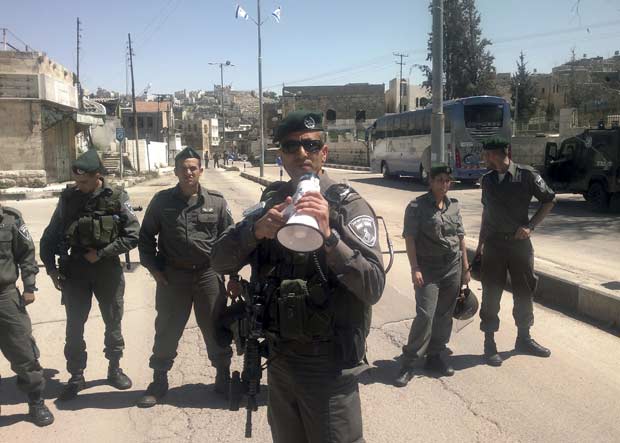 Policial de fronteira usa megafone para ordenar saída de colonos judeus de casa em Hebron, na Cisjordânia, nesta quarta-feira (4) (Foto: Reuters)