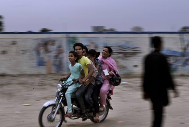 Cinco pessoas foram flagradas andando em uma moto nesta sexta-feira (6) em um bairro em Islamabad, no Paquistão. Uma das crianças parece esconder o rosto após a família ser fotografada durante o passeio. (Foto: Muhammed Muheisen/AP)