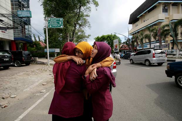 Mulheres se abraçam em Banda Aceh logo após a notícia do terremoto e do alerta de tsunami nesta quarta-feira (11) (Foto: AFP)