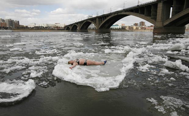 Mulher usa bloco de gelo flutuante como se fosse uma boia. (Foto: Ilya Naymushin/Reuters)
