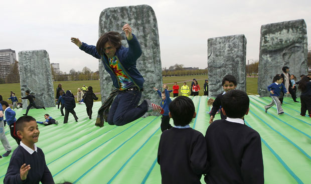 O artista Jeremy Deller, que aparece pulando entre crianças, criou um enorme pula-pula reproduzindo o Stonehenge, antiga estrutura de rochas que é ponto turístico e místico no país. (Foto: David Moir/Reuters)
