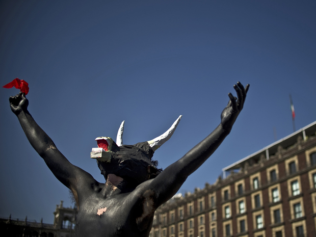 Um ativista usando uma máscara de touro participa de protesto contra briga de touros na praça Zocalo, na cidade do México, neste domingo (22). Os manifestantes pedem que os legisladores acabem com a prática no México (Foto: AFP)