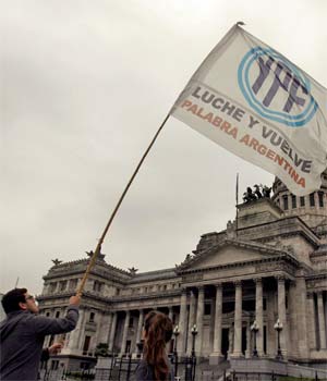 Jovem agita bandeira da petroleira YPF em frente ao Congresso da Argentina (Foto: Reuters)