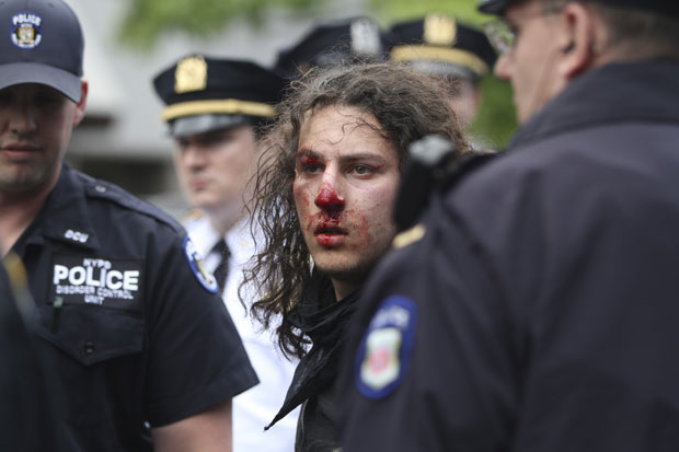 Jovem com sangue no nariz é detido pelos policiais (Foto: Mary Altaffer/AP)