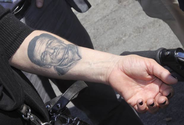 Mulher mostra tatuagem com o rosto de seu marido em protesto contra a crise financeira na Itália nesta sexta-feira (4) em Bolonha. Ela afirma que ele se matou por causa da crise (Foto: Giorgio Benvenuti/Reuters)