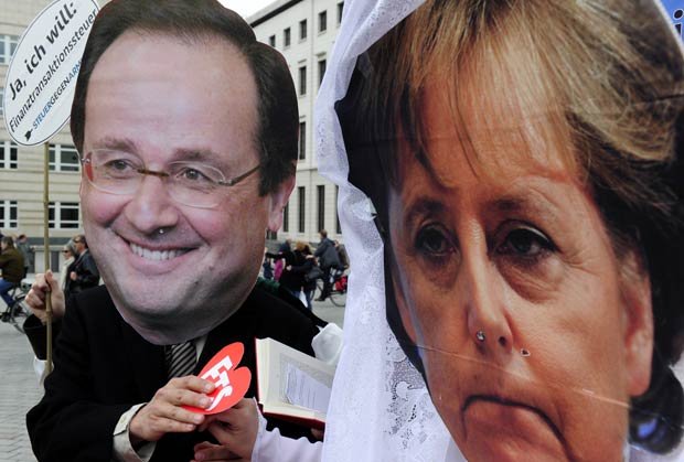 Manifestantes com máscaram encenam o 'casamento' entre o presidente eleito francês, François Hollande, e a chanceler alemã, Angela Merkel, nesta segunda-feira (7) em Berlim (Foto: AFP)