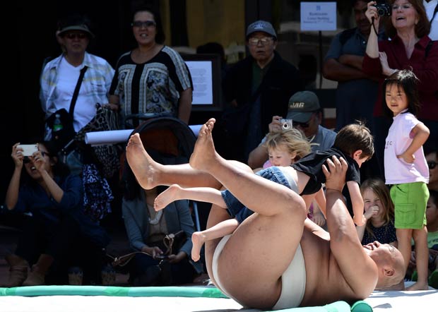O tricampeão mundial de sumô Byamba ensina sua técnica a crianças nesta sexta-feira (5) em Los Angeles (Foto: AFP)