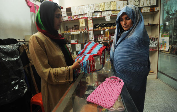 Mulher observa o trabalho pronto da afegã (Foto: Aref Karimi/AFP)