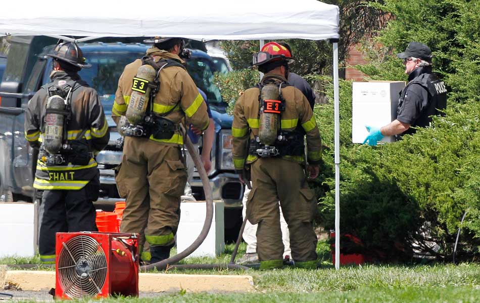 21 de julho - Junto a bombeiros, policial carrega caixa com químicos das armadilhas montadas no apartamento do atirador dos EUA.