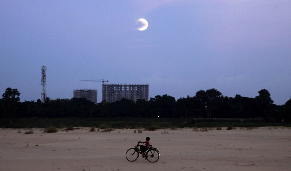 Menino passeia de bicicleta com a lua azul brilhando nos arredores da cidade indiana de Bhubaneswar.