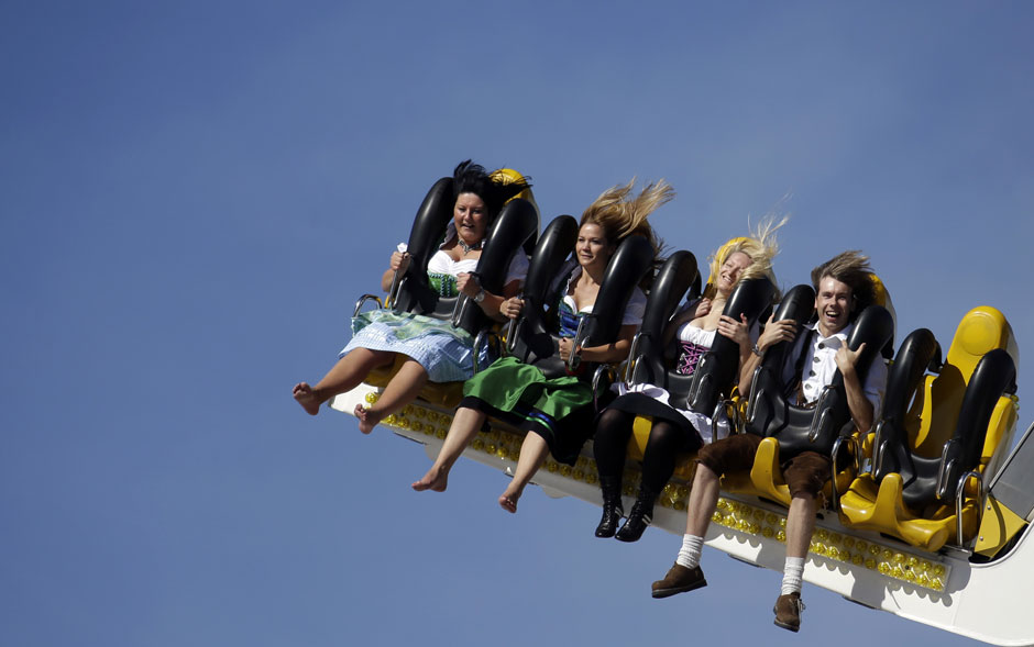 25 de setembro - Grupo se diverte em atração de parque de diversões da Oktoberfest vestindo roupas tradicionais da Bavária