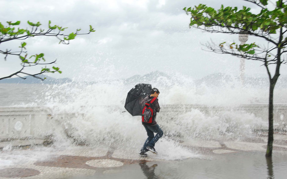Pedestre é atingido por ondas que invadiram a calçada na ressaca do mar em Santos, no litoral de São Paulo.