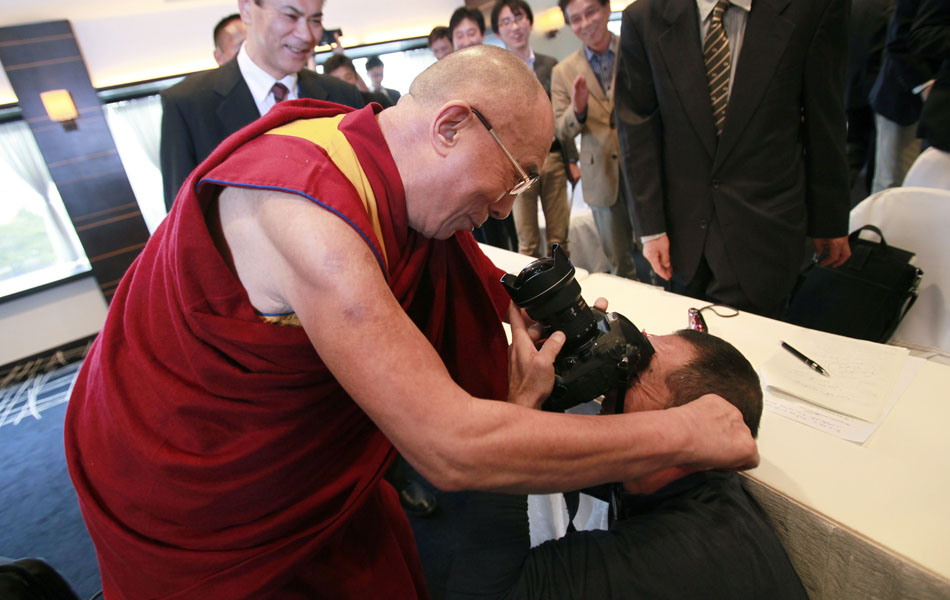O líder tibetano Dalai Lama puxa orelha de um fotógrafo durante coletiva de imprensa em Yokohama, no Japão.